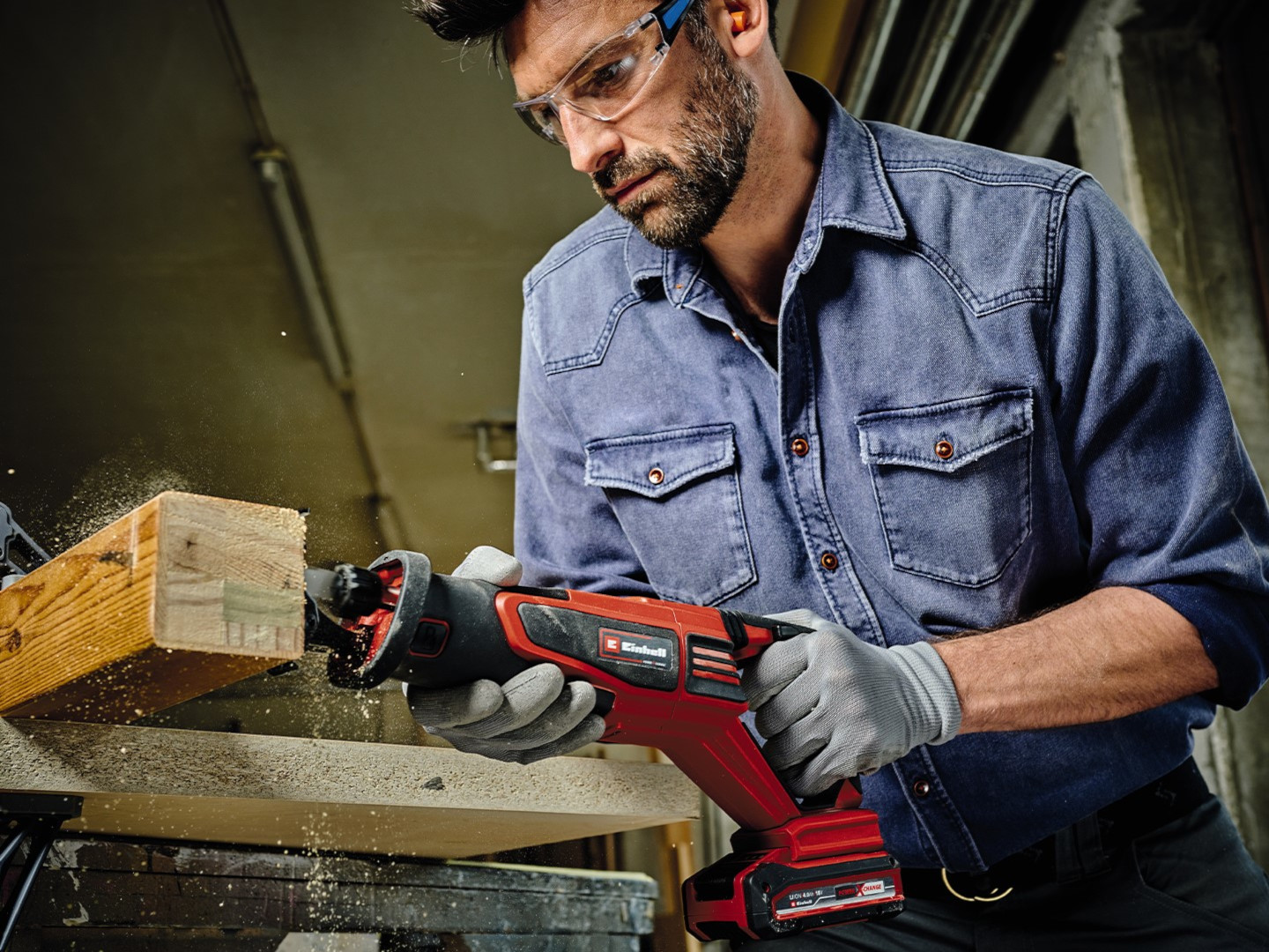 A man uses a battery-powered saw