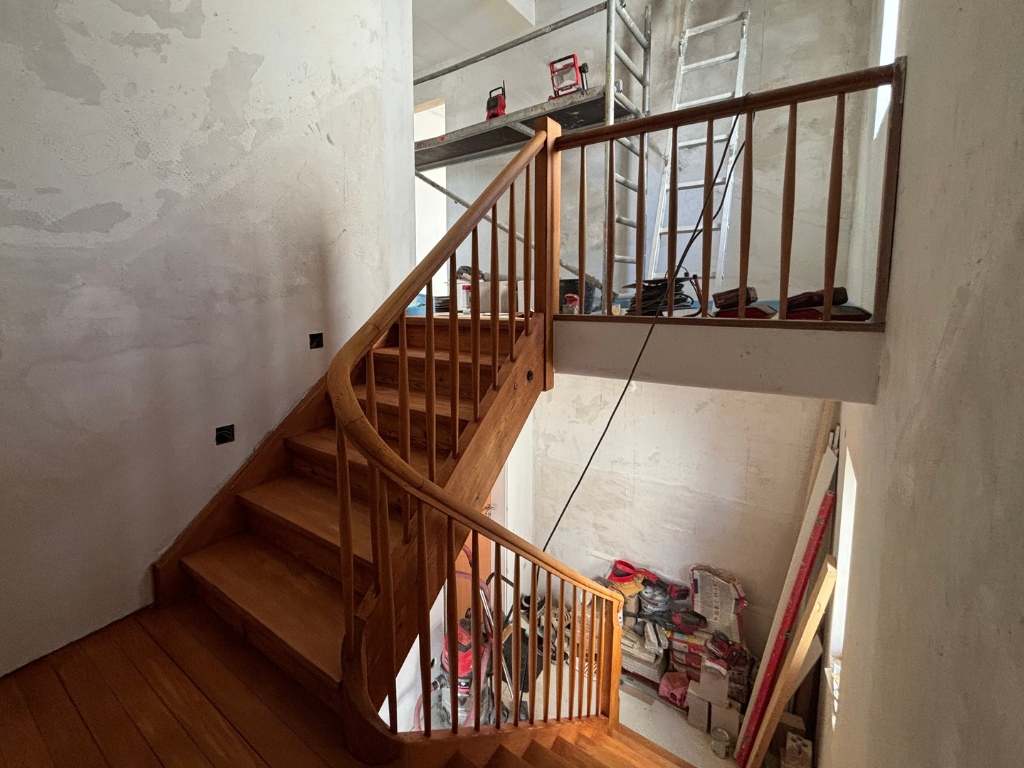 Geschliffene Holztreppe mit Geländer im Innenbereich während der Renovierung.
