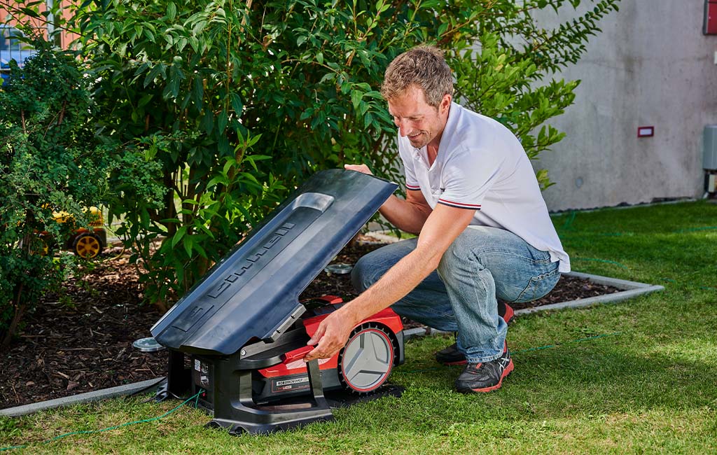 A man installing a robotic lawnmower garage in his garden.