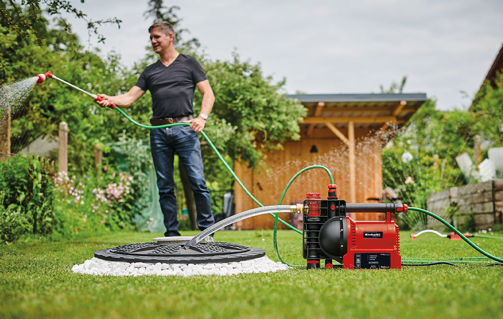 A man sprays water in a garden with an automatic garden pump.