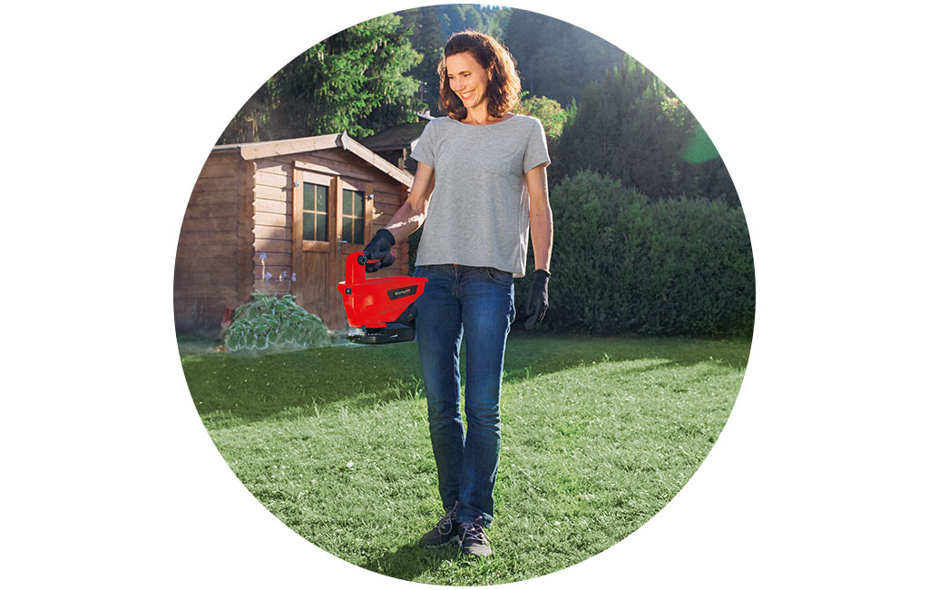 A woman fertilizes the lawn with the Einhell universal spreader.