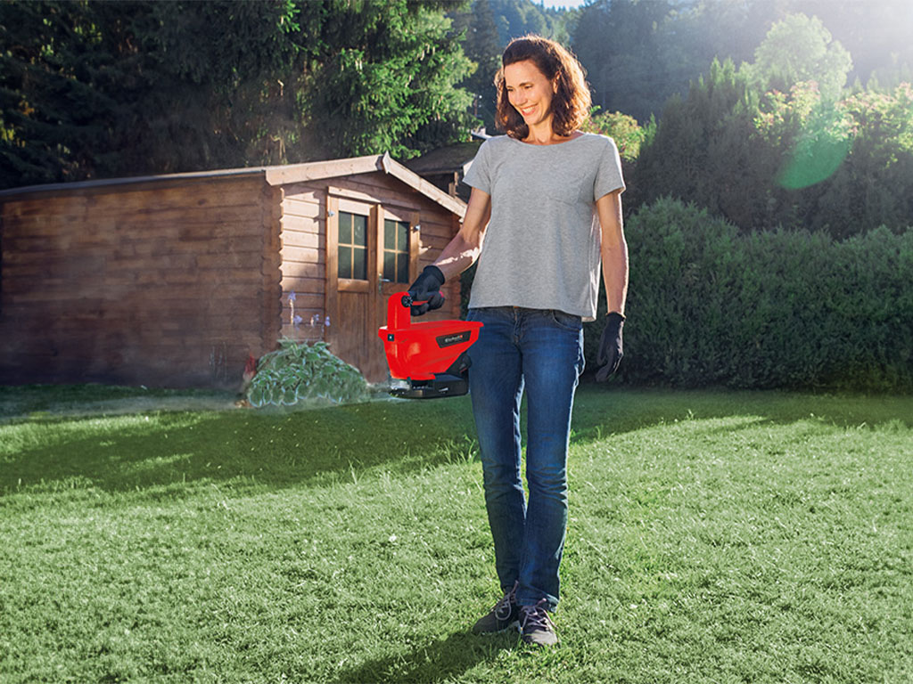 a woman fertilizes the lawn with the Einhell universal spreader