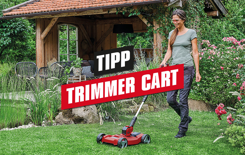 a woman is mowing the lawn with a Einhell cordless lawn trimmer with its trimmer cart