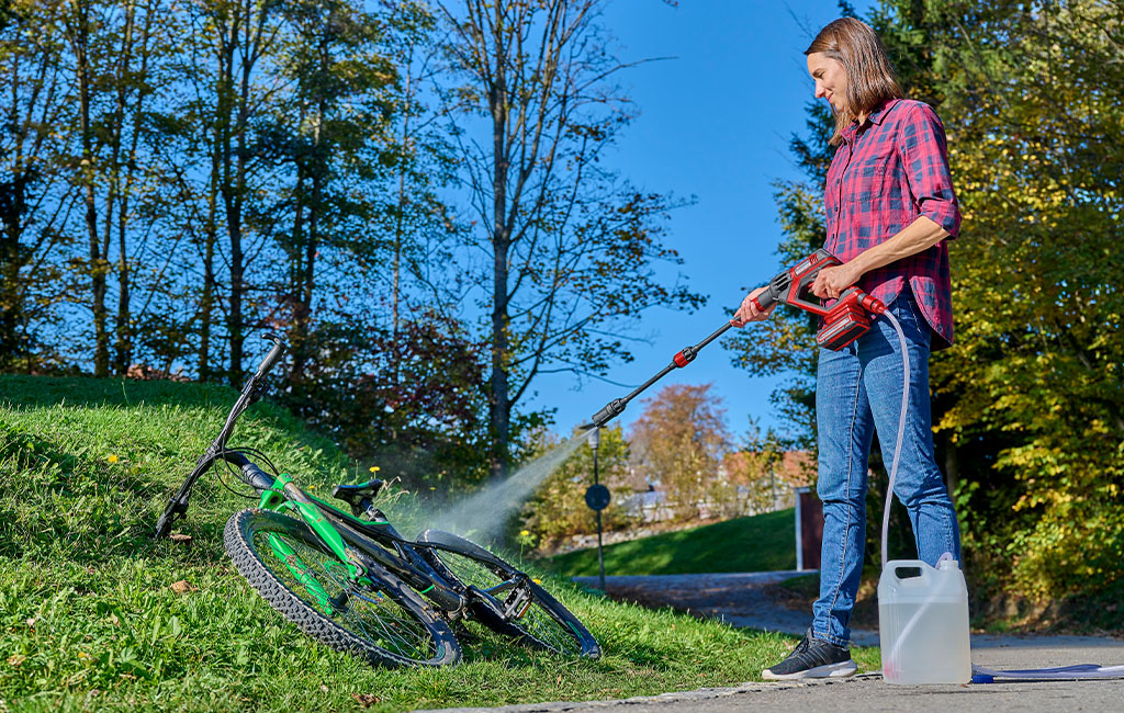 a woman cleans a bicycle with the Einhell HYPRESSO