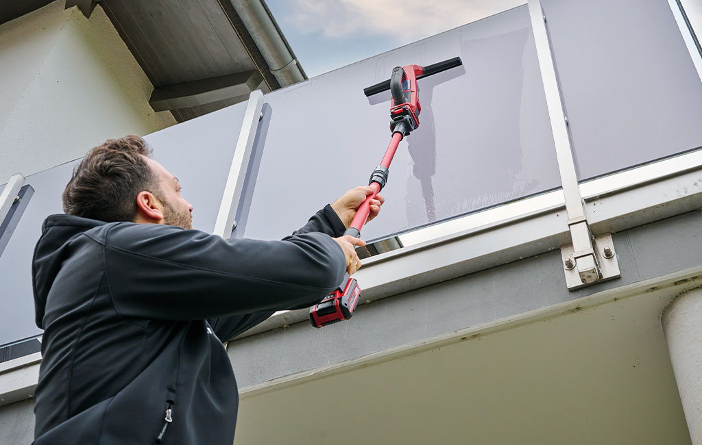 a man i using the telescopic handle on a higher window pane