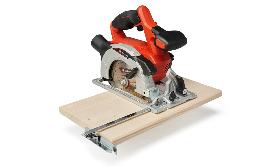 A handheld circular saw on a piece of wood with a guide rail.