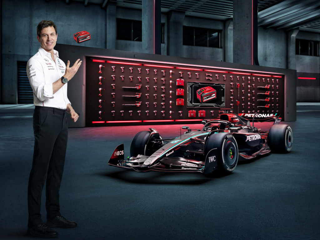 Toto Wolff throws a battery into the air next to a Formula One car