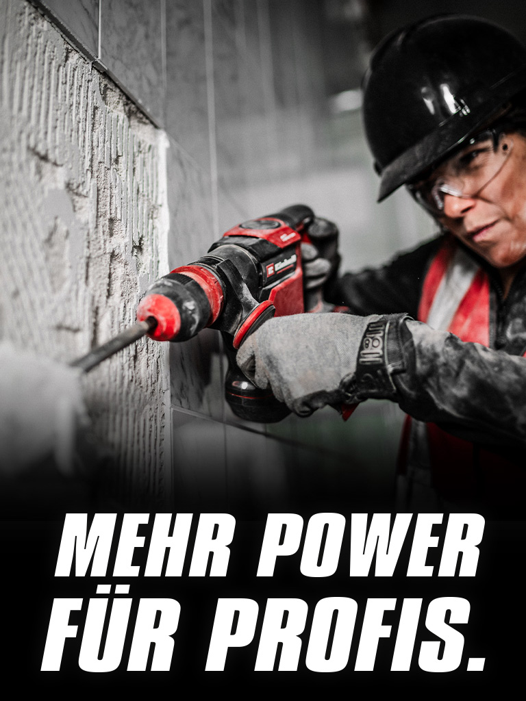 Eine Person mit Schutzbrille und Helm verwendet eine rote Bohrmaschine an einer Wand, mit dem Text "Mehr Power für Profis".