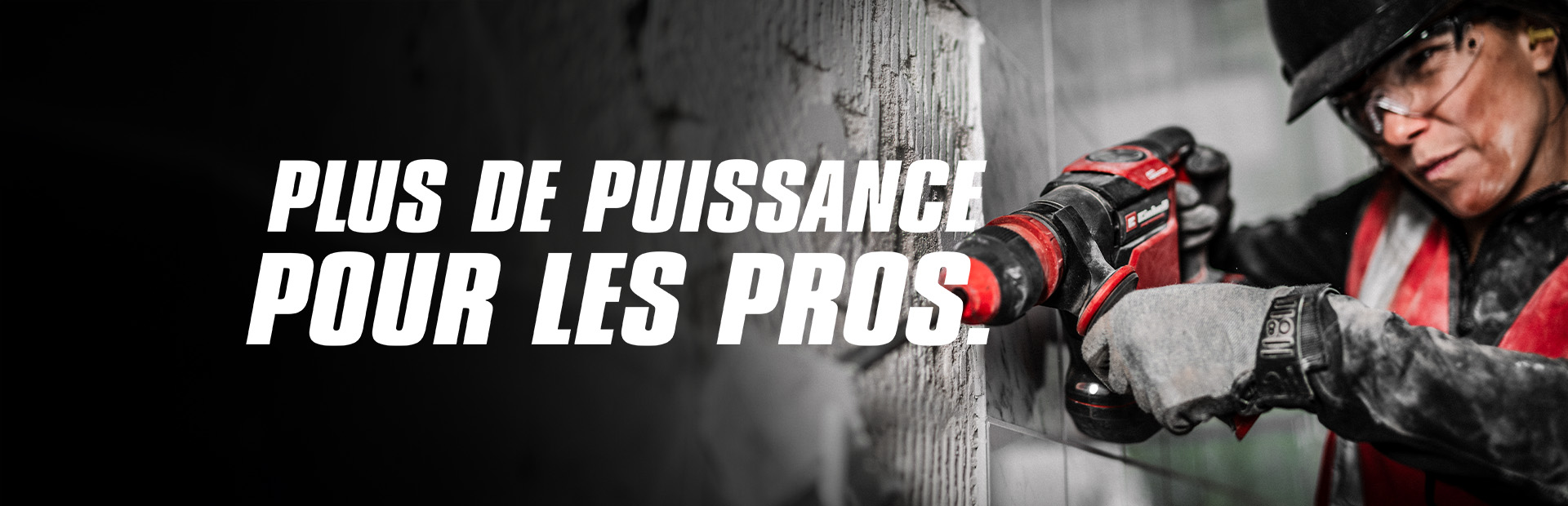 Une personne portant des lunettes de sécurité et un casque utilise une perceuse rouge sur un mur, avec le texte "Plus de puissance pour les pros".