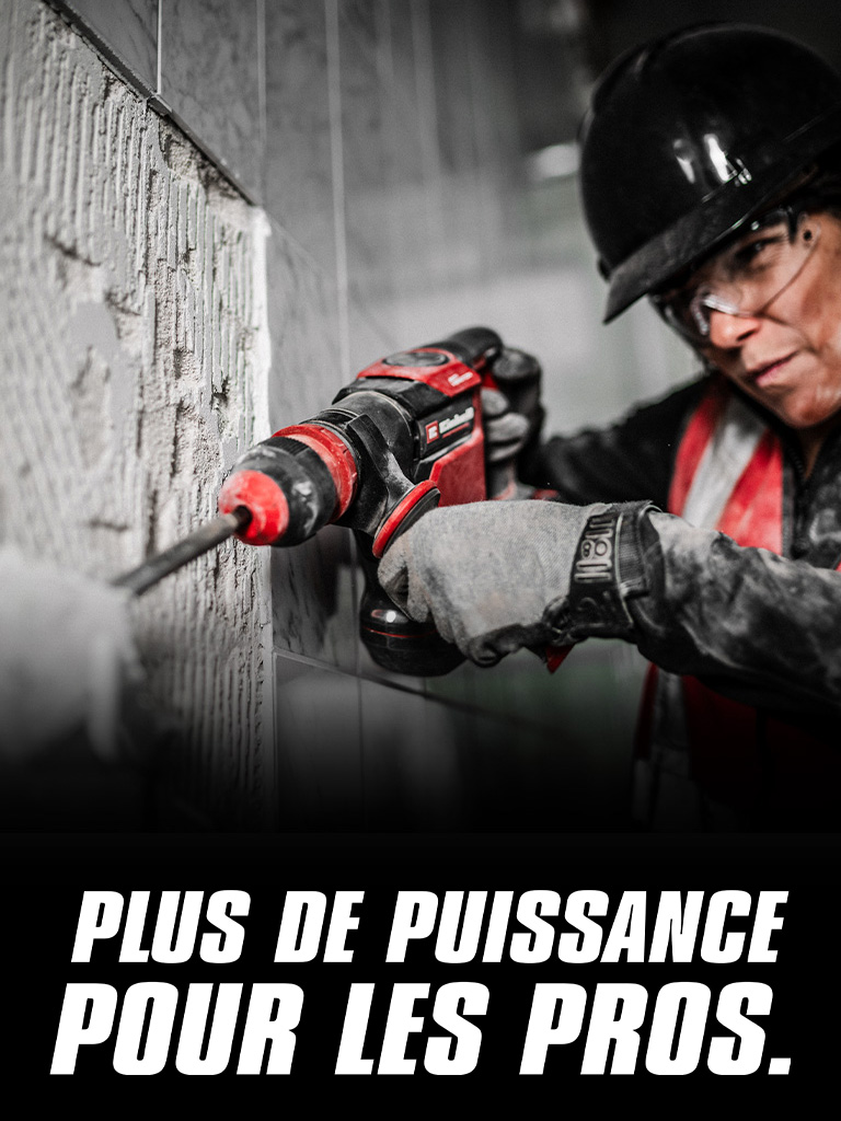 Une personne portant des lunettes de sécurité et un casque utilise une perceuse rouge sur un mur, avec le texte "Plus de puissance pour les pros".