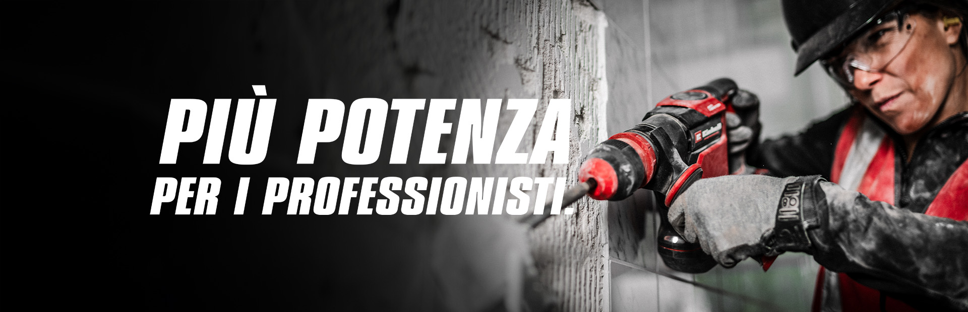 Una persona con occhiali di sicurezza e casco utilizza un trapano rosso su una parete, con il testo "Più potenza per i professionisti".