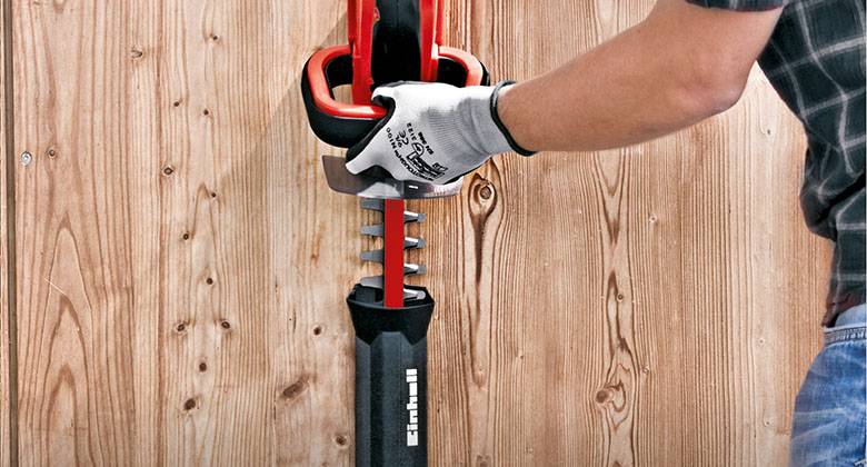 man putting hedge trimmer knive in protective cover 