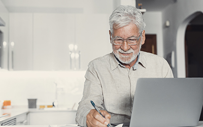 An elderly man writing something down.